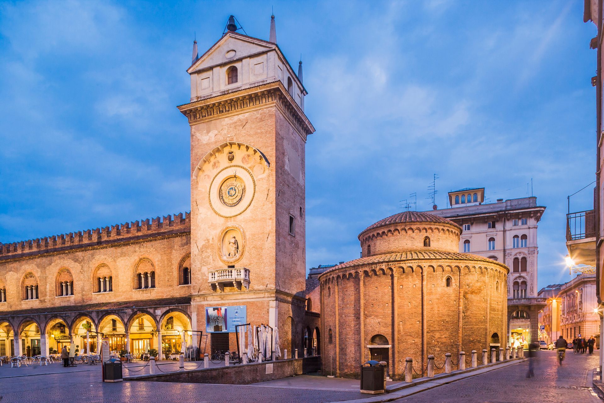 Torre dell'orologio e rotonda di Mantova, Italia, illuminate al tramonto.