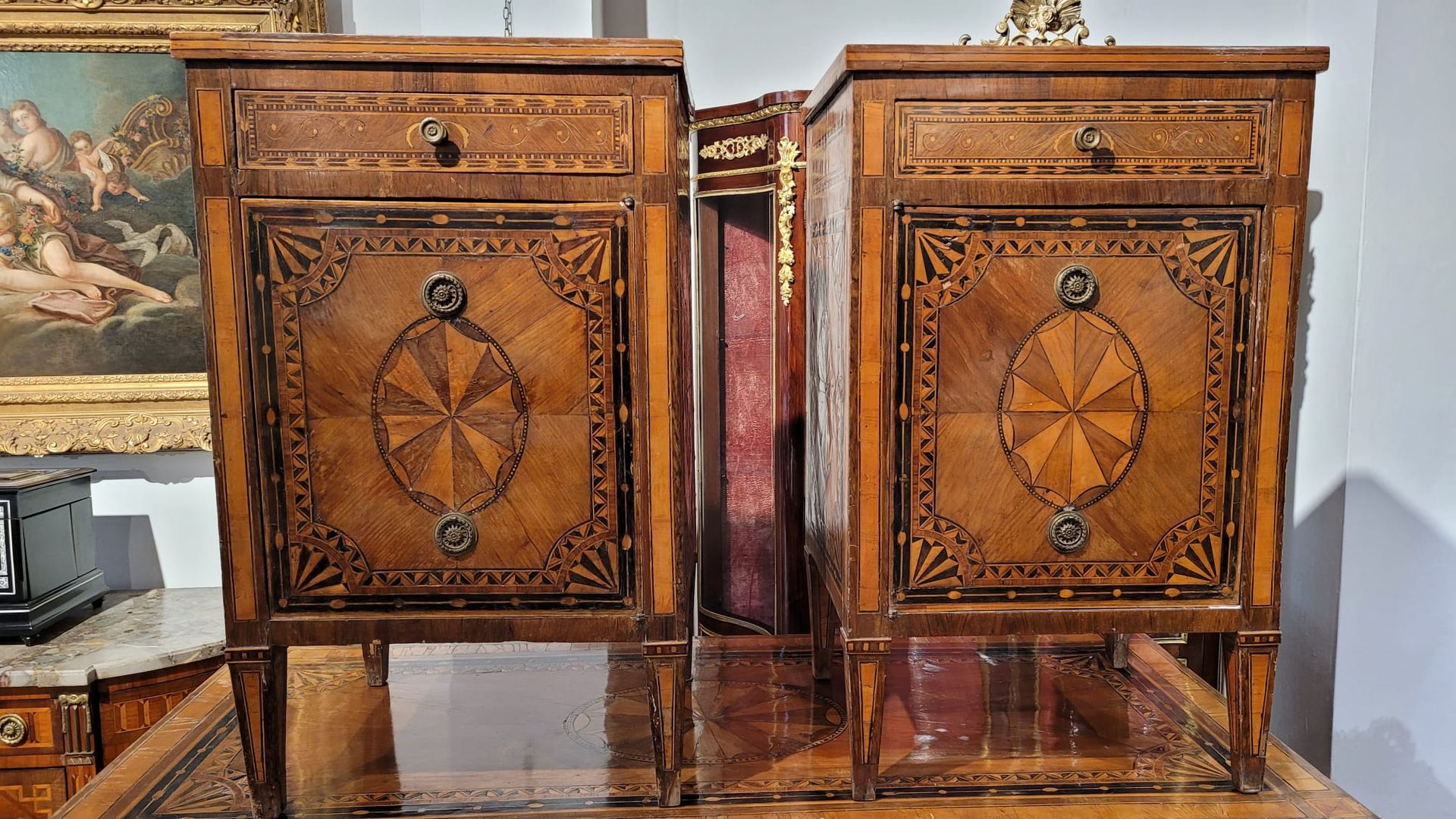 Due comodini in legno decorato con cassetto e intricati motivi intarsiati.