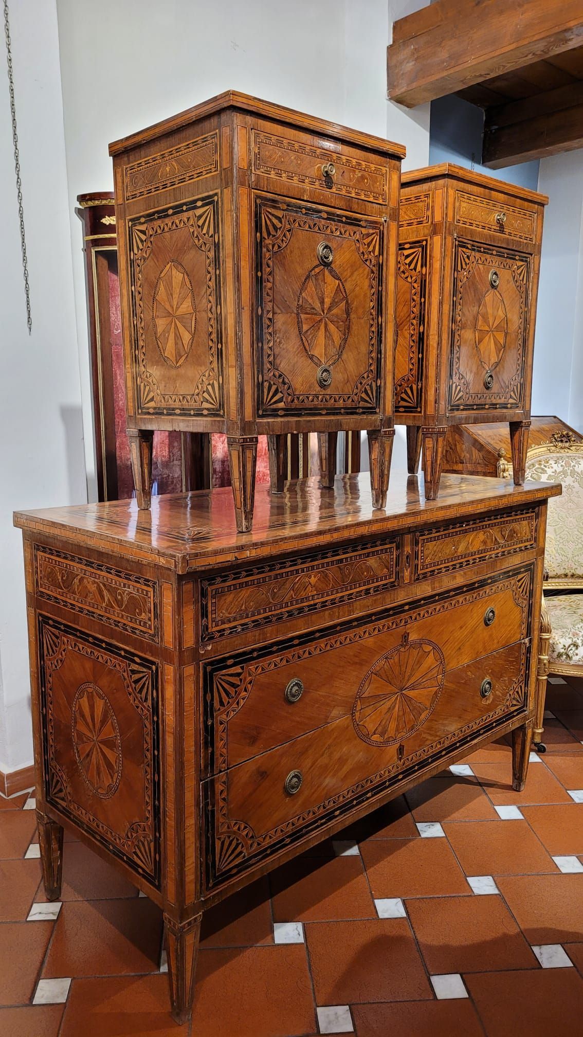 Set di mobili antichi in legno con intarsi floreali, comprendente una cassettiera e due armadietti.