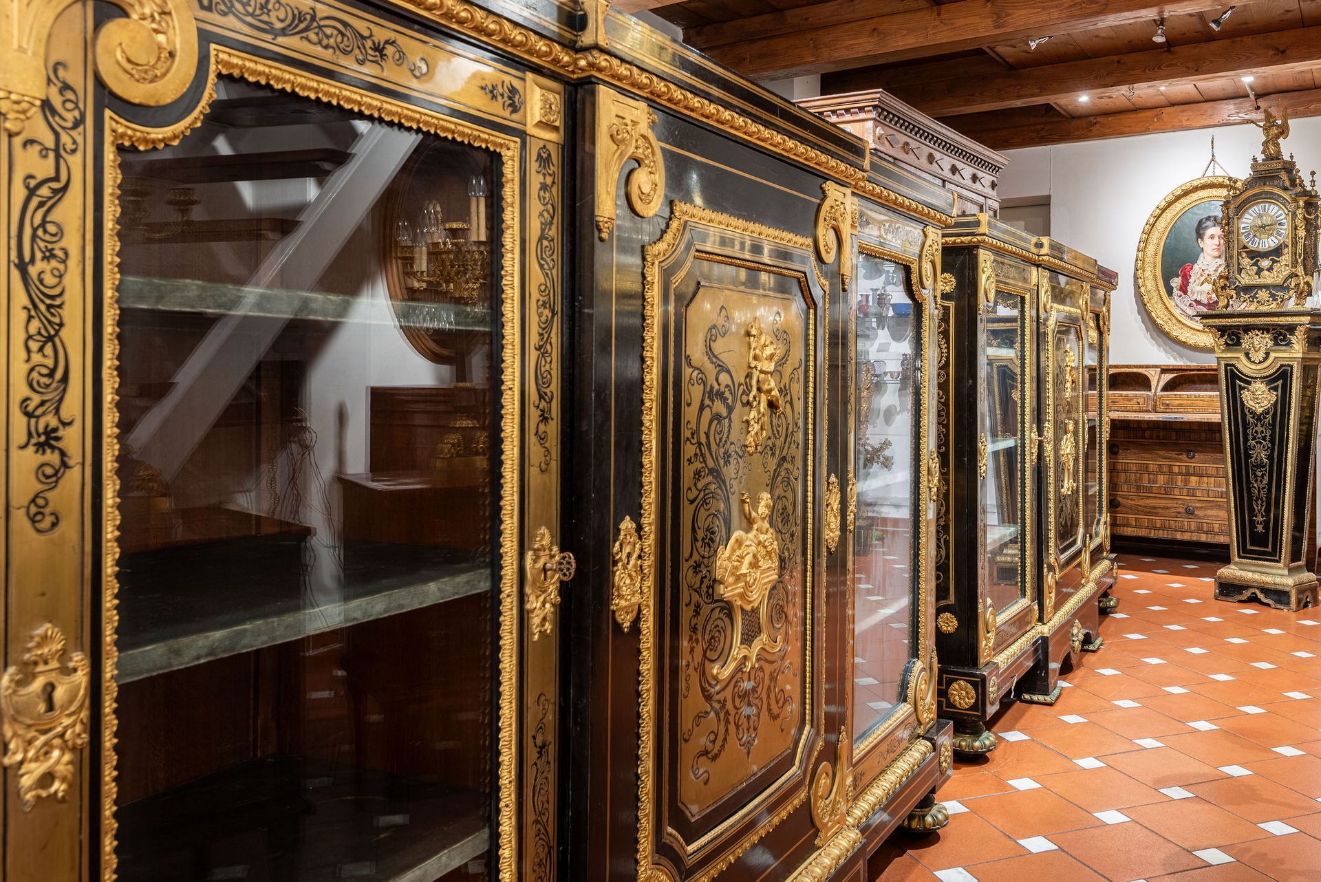 Mobili decorati neri e dorati con ante in vetro in una stanza, con pavimento in marmo e orologio antico.