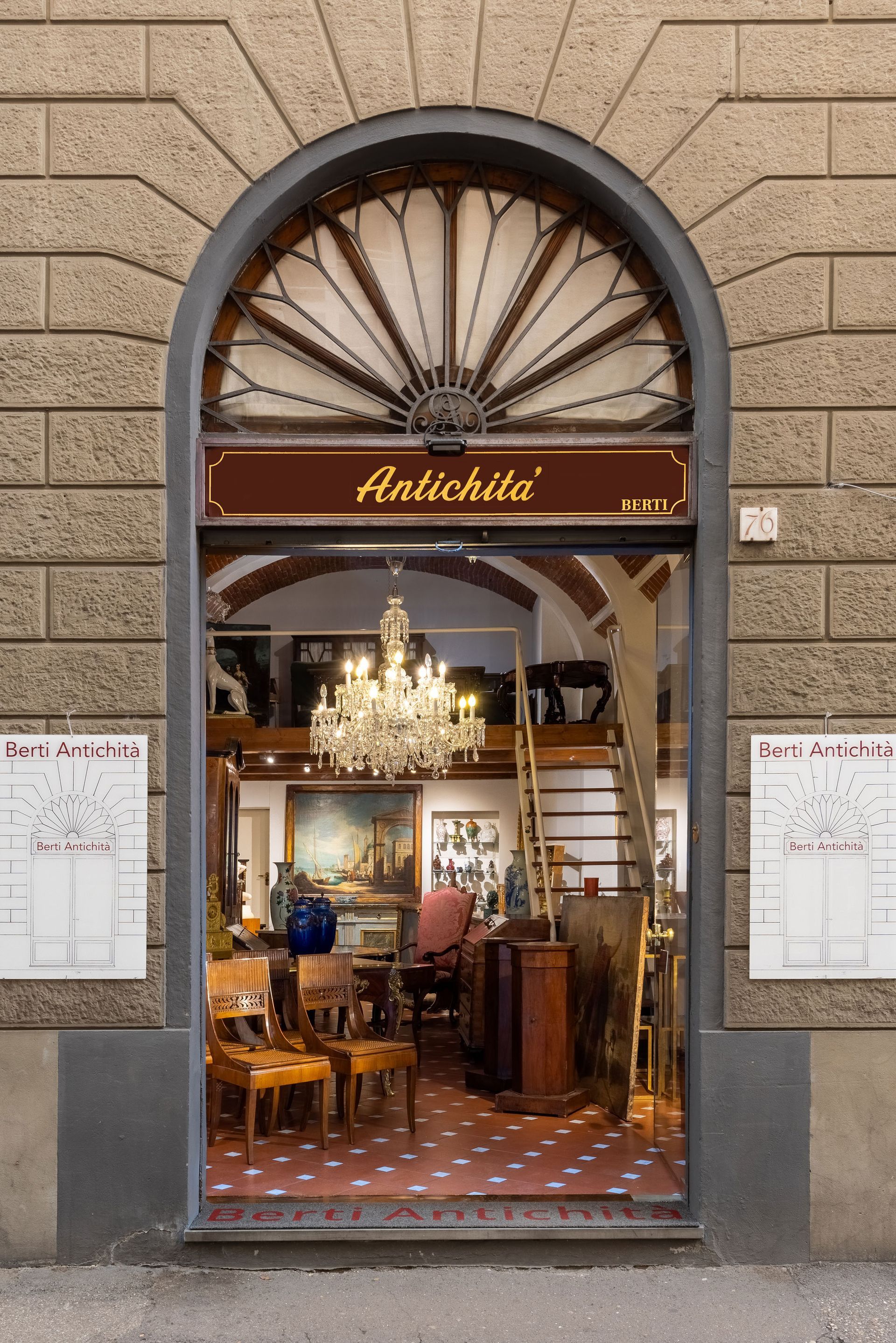 Ingresso di un negozio di antiquariato con porta ad arco e lampadario decorato. Insegna