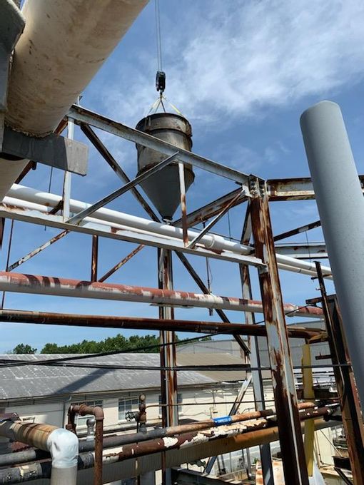 A large metal structure with pipes and a crane in the background