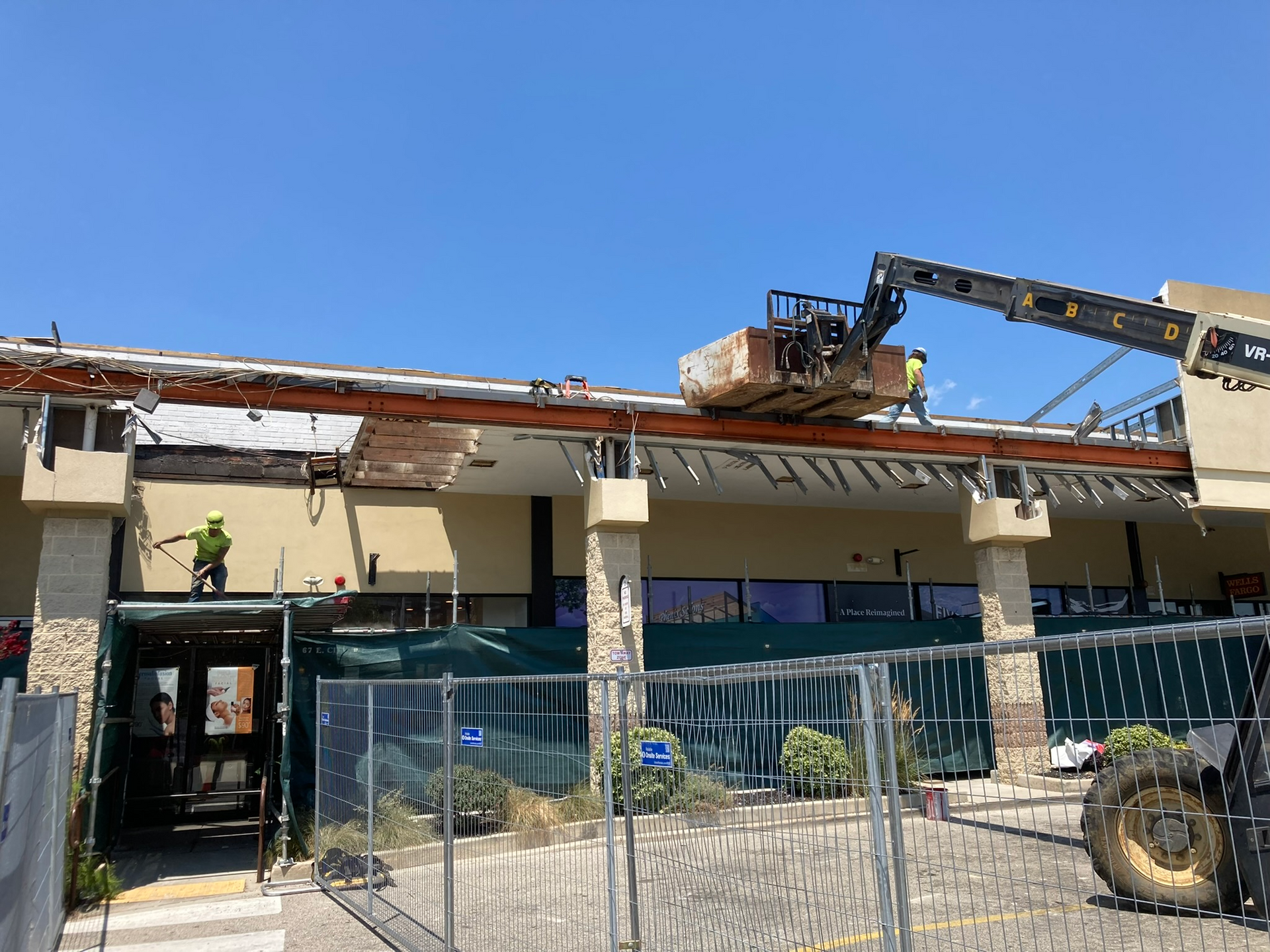 A large building is being demolished with a crane and a tractor.