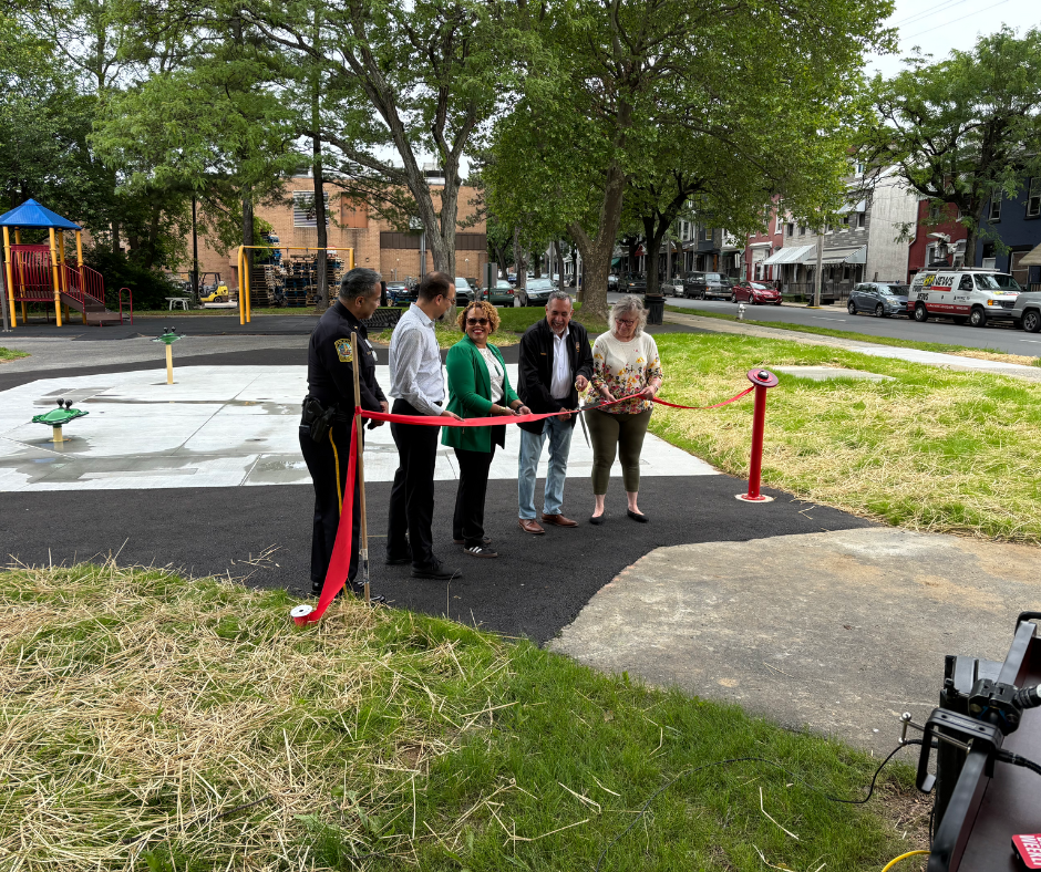 People cutting a red ribbon at a playground opening.