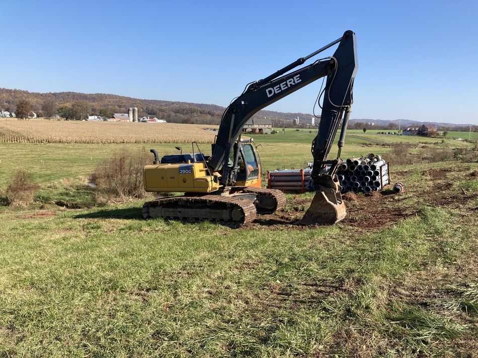 A large yellow excavator is sitting in the middle of a grassy field.