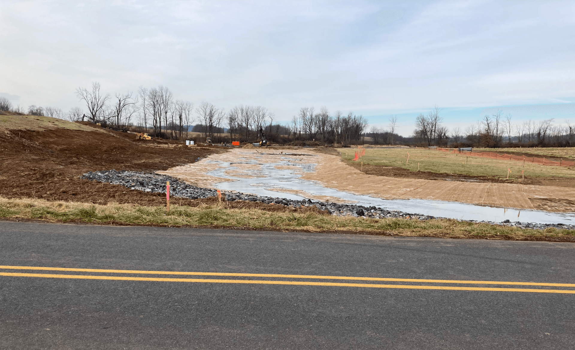 A road with a lot of water on the side of it and a field in the background.