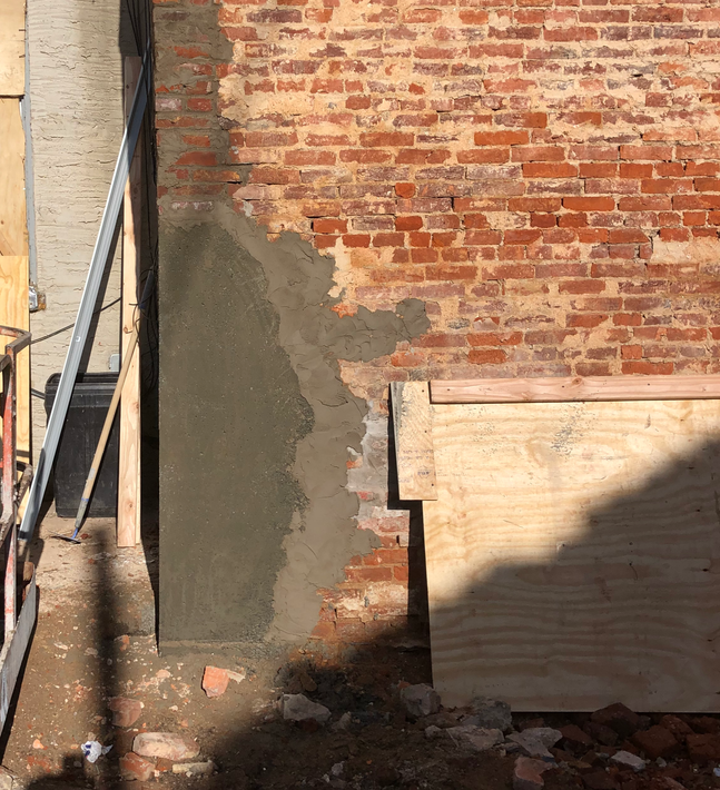 A brick wall with concrete being poured on it
