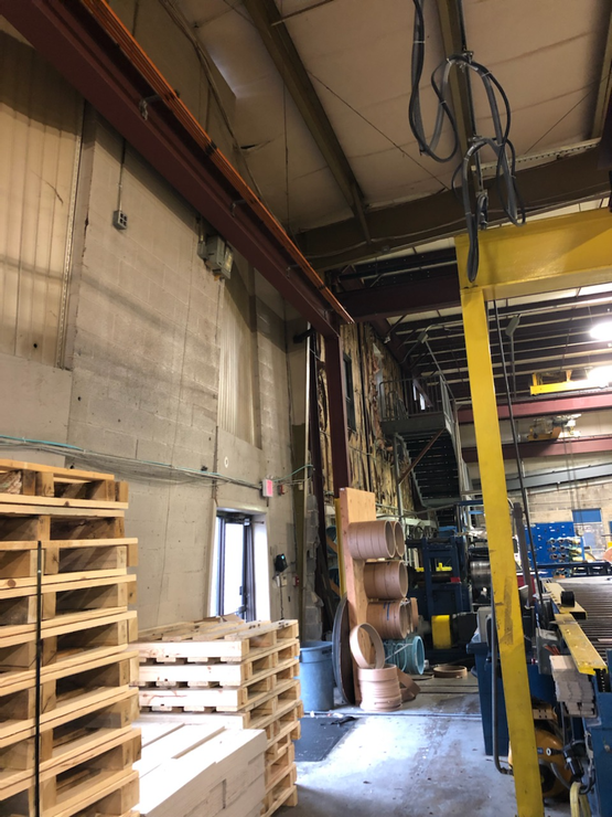 A warehouse with wooden pallets and a yellow crane