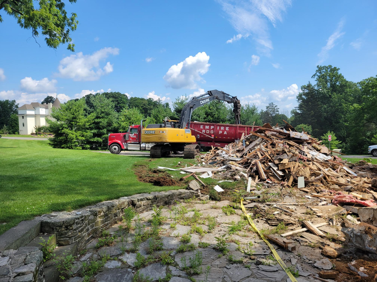 A large pile of wood is being loaded into a dumpster.