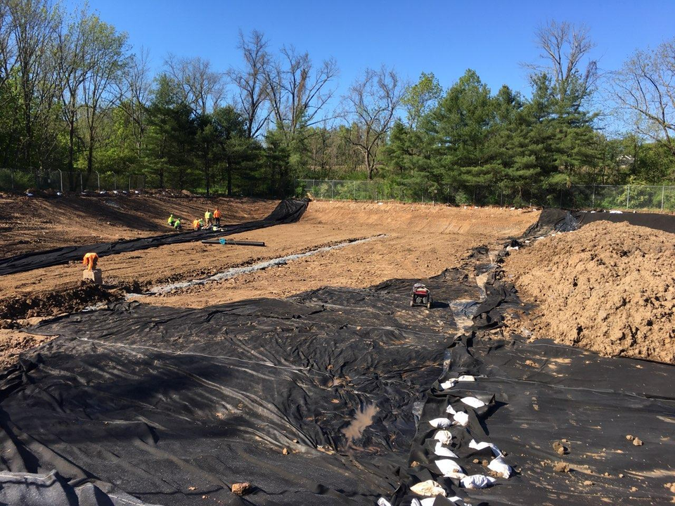 A construction site with a lot of dirt and trees in the background.