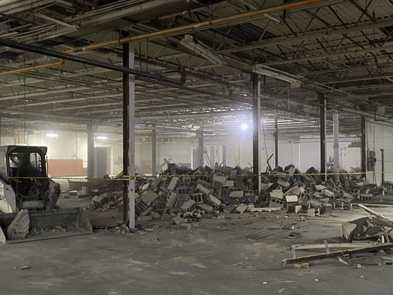 An empty warehouse with a bulldozer in the middle of it.