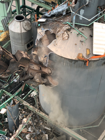 A large tank is being demolished in a factory.