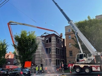 A crane is being used to pour concrete on top of a building