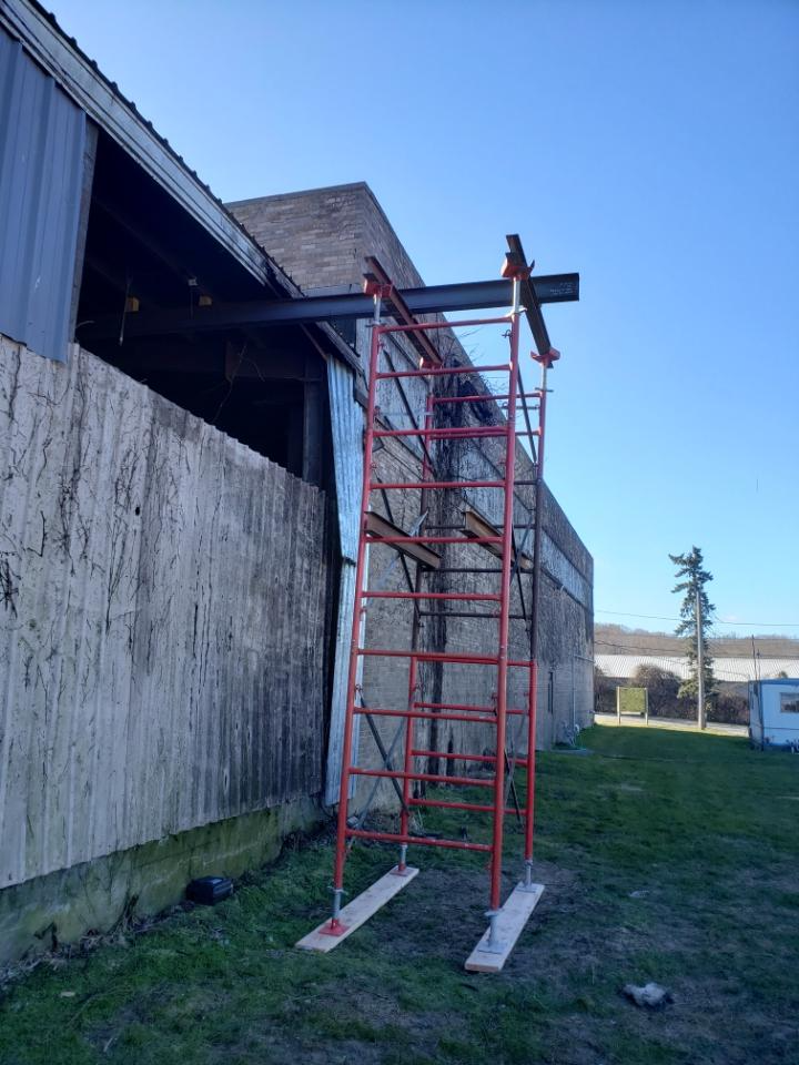 A man is standing on a ladder in front of a building