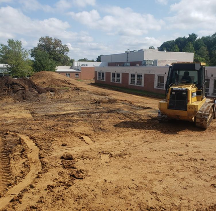 A bulldozer is sitting in the dirt in front of a building
