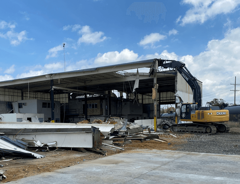 A large building is being demolished by a large excavator.