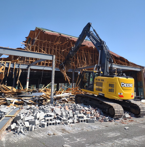 A yellow deere excavator is demolishing a building