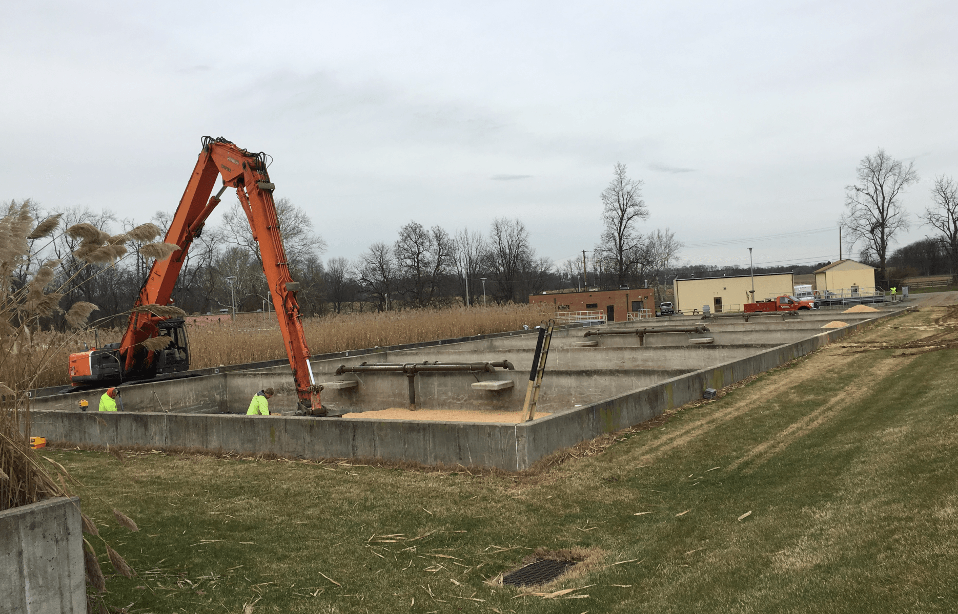 A large orange excavator is sitting on top of a concrete foundation.