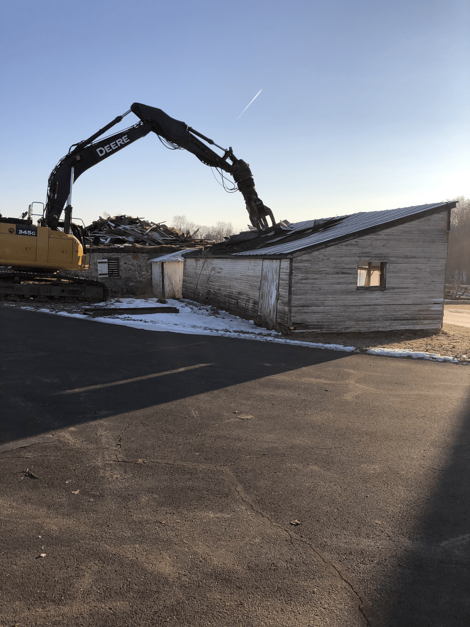A large yellow excavator is demolishing a building.