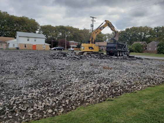 A large yellow excavator is loading gravel into a dump truck.