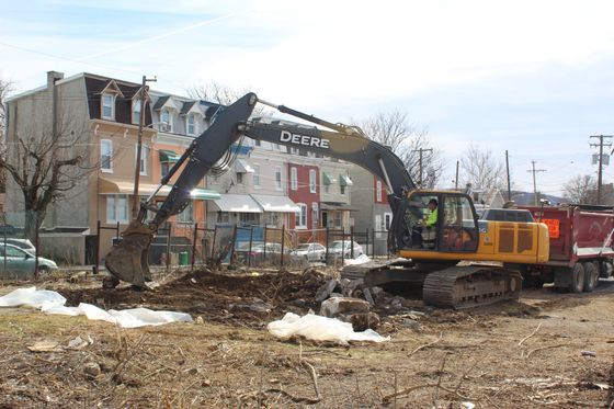 A deere excavator is digging a hole in a dirt field.