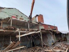 A large building is being demolished by a crane.