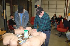 A group of men are sitting around a table with mannequins.