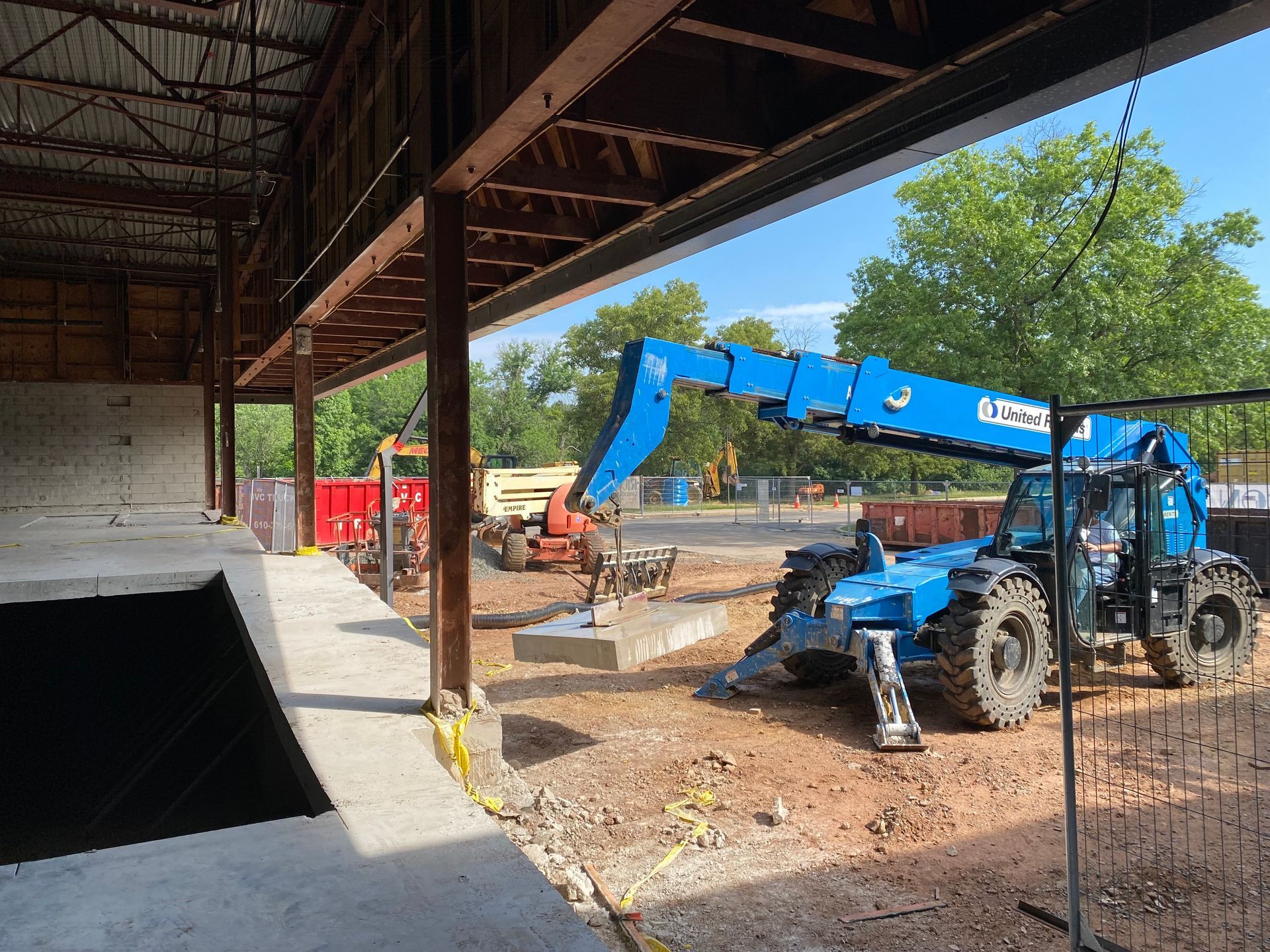 A blue forklift is parked in front of a building under construction.