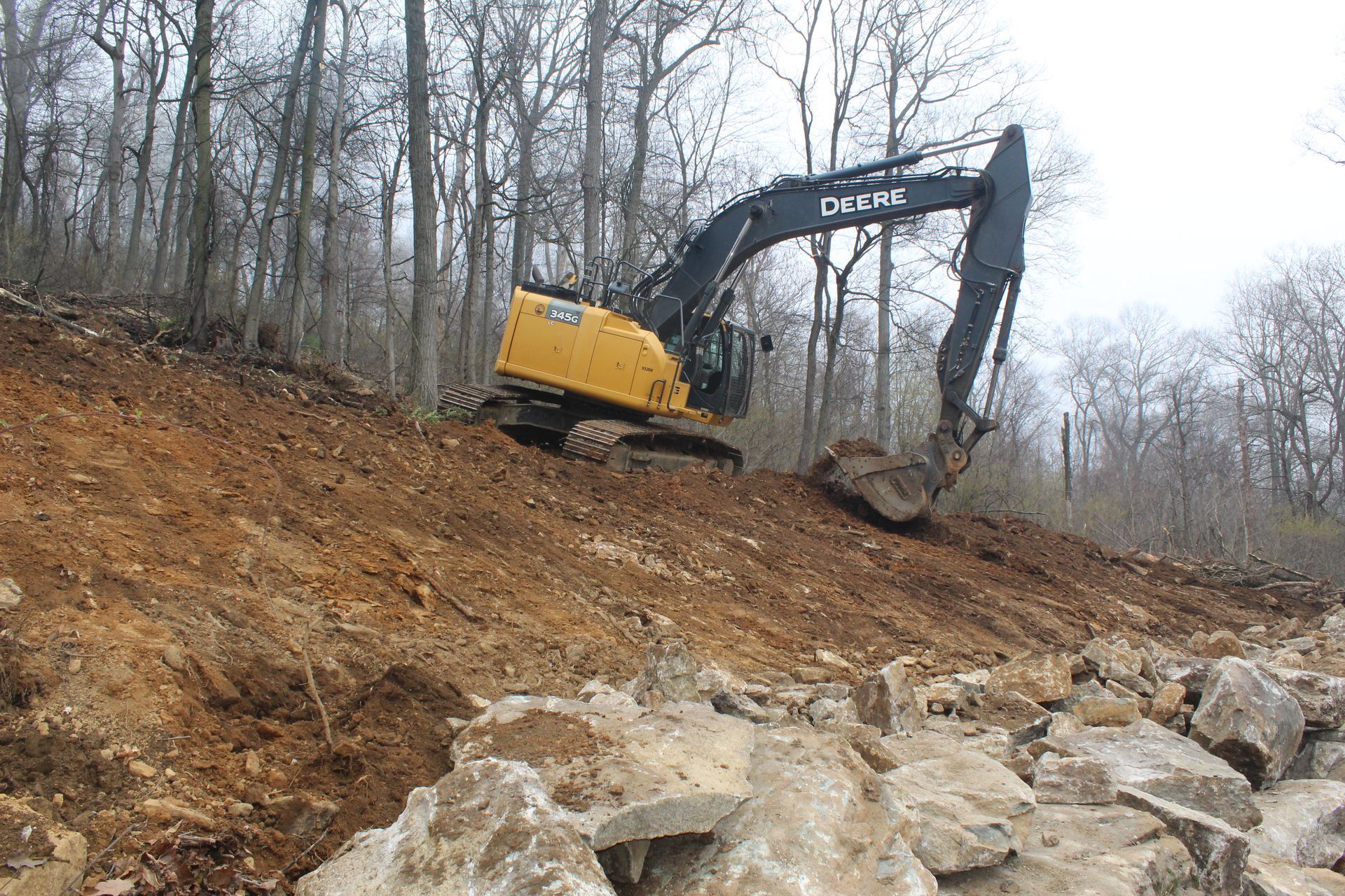 clearing trees and rocks above rock barrier 
