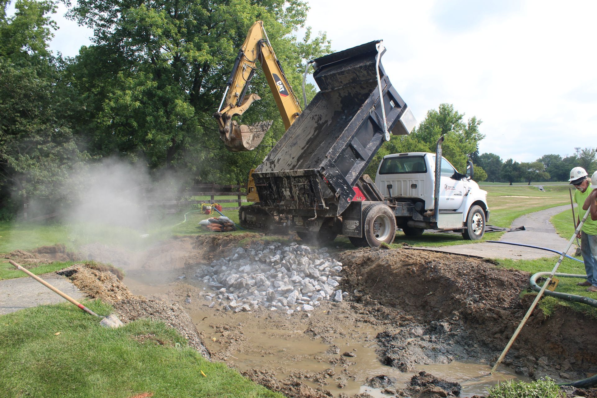 Larger stone is placed on top of the culvert piping.