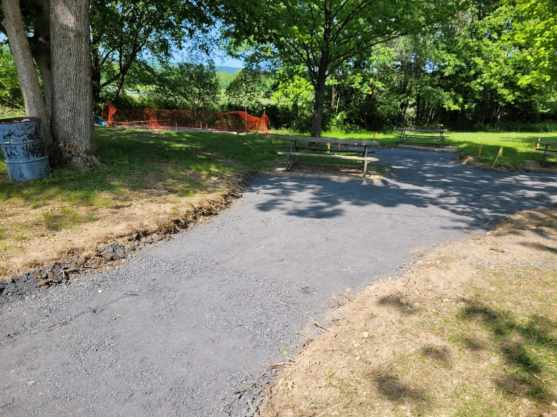 A dirt road leading to a picnic table in a park.
