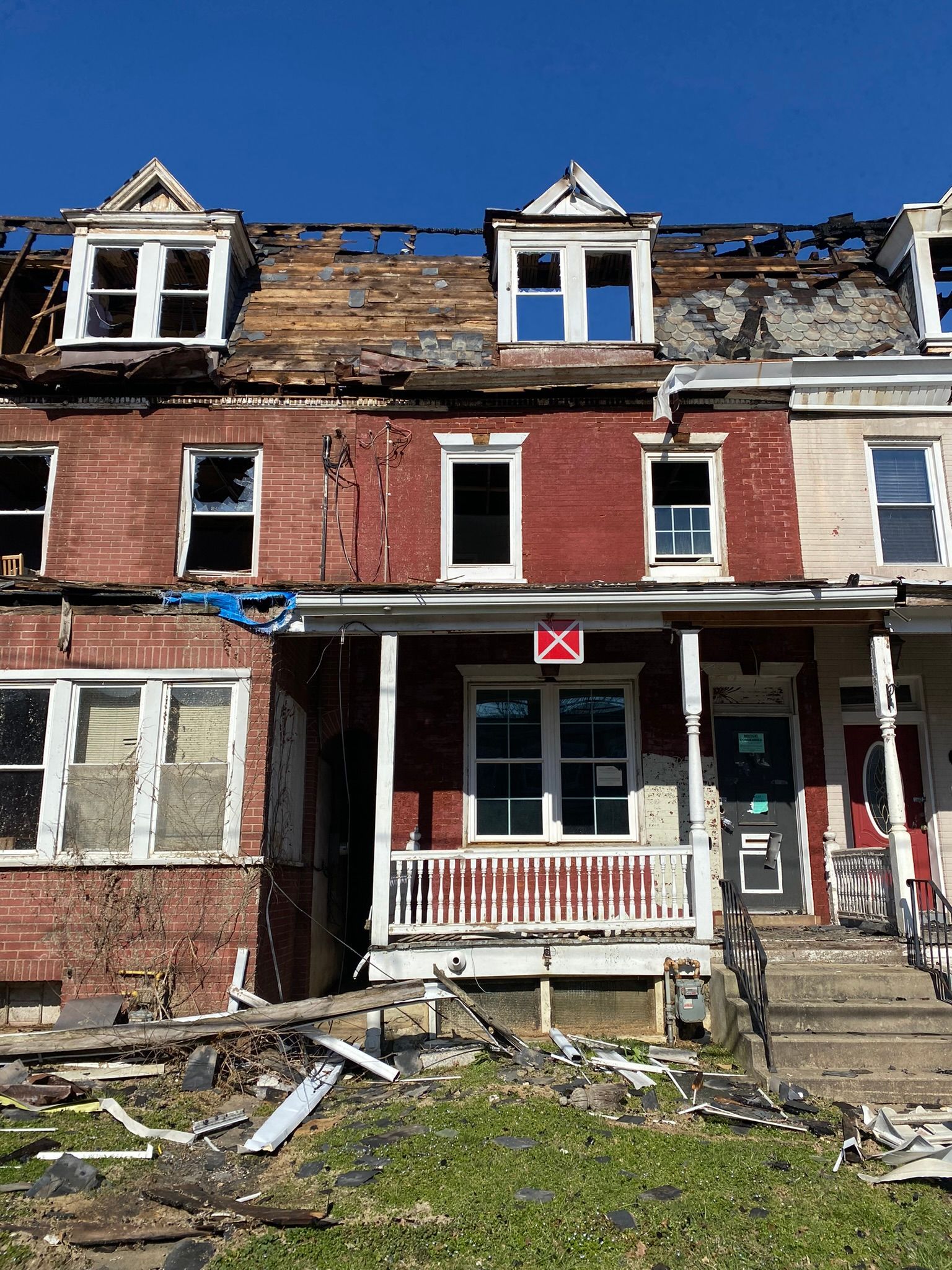 A red brick house with a white porch is being demolished.