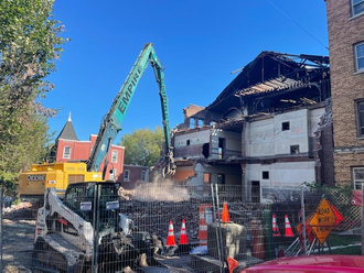 A bulldozer is demolishing a building in a city.
