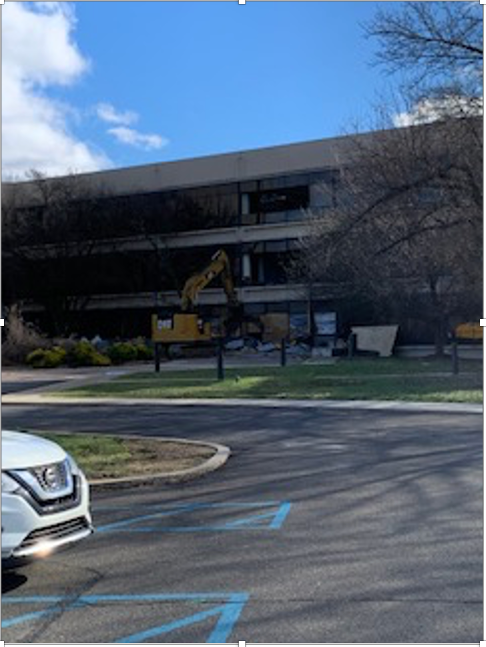 A white car is parked in front of a building under construction