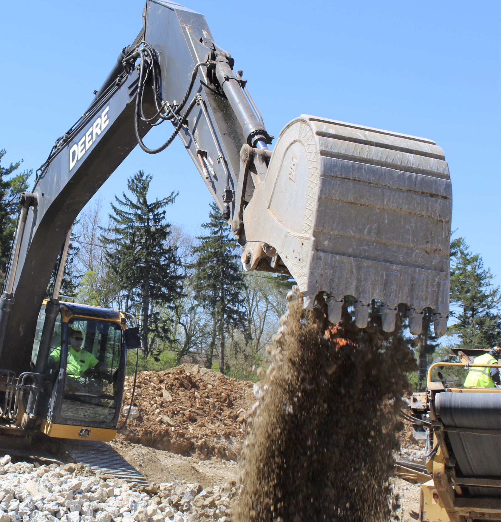A deere excavator is scooping dirt out of its bucket