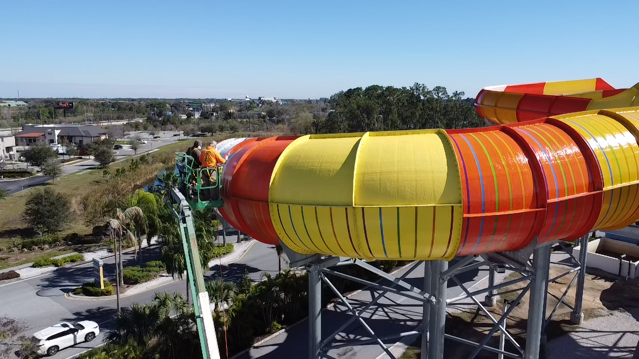 High-elevation waterslide installation with yellow and orange enclosed tube