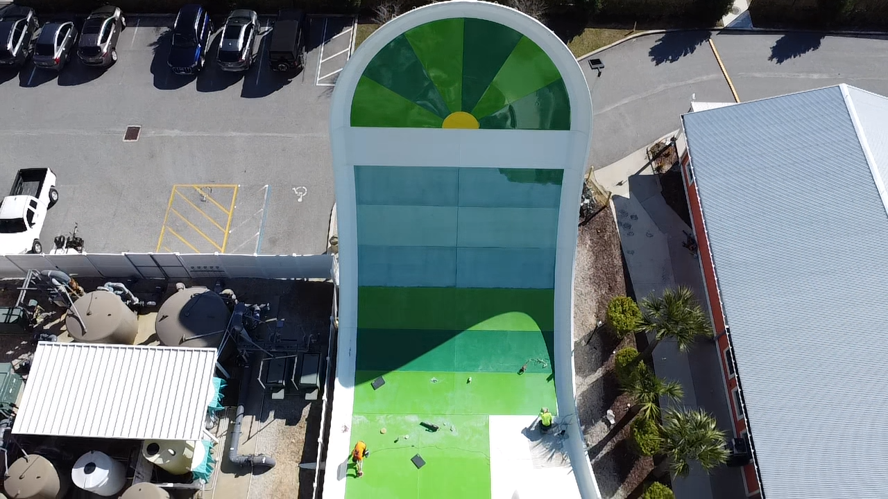 Aerial view of crew preparing green drop-slide attraction for opening