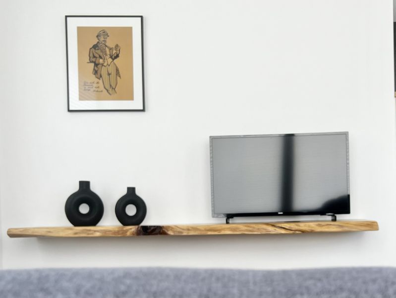 Flachbild-Fernseher auf einem modernen Holz-TV-Board mit Dekoration in der Ferienwohnung