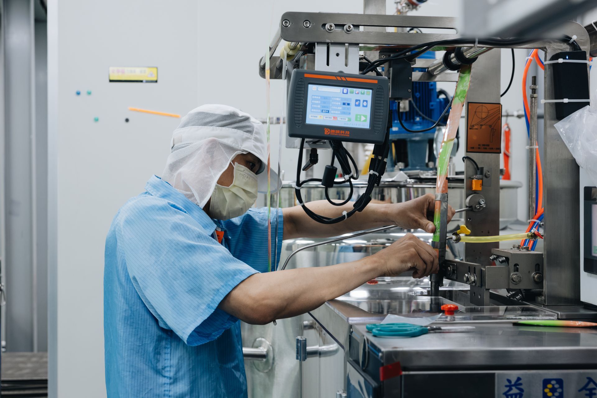 統荃生醫技術人員於無塵車間操作高精密背封充填機台。引進全台領先背封技術與自動化殺菌設備,為液體軟袋代工提供絕不漏液保證,降低創業客訴與風險。