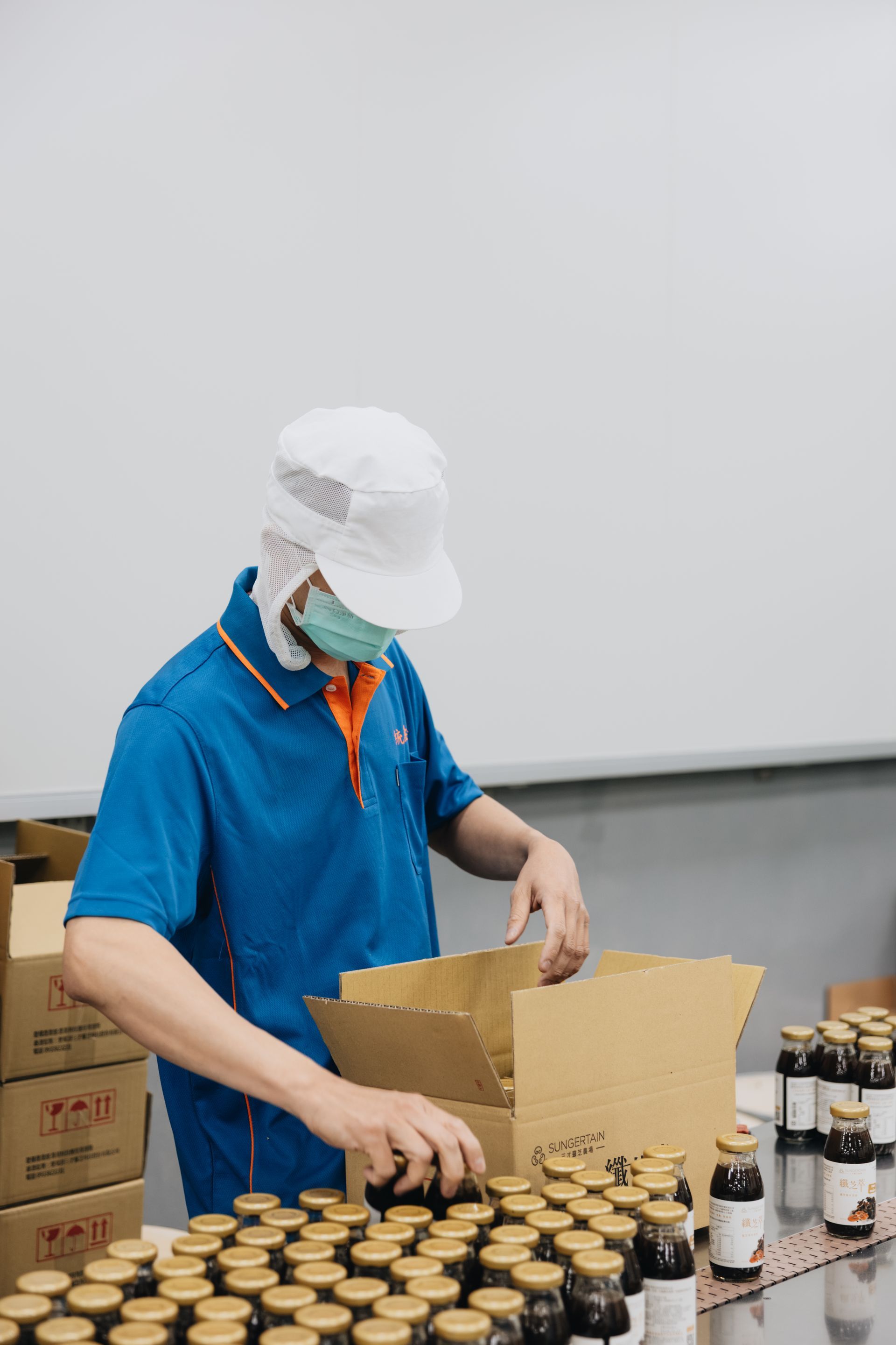 統荃生醫生產車間工作人員進行玻璃瓶裝機能飲品之包裝與品管檢驗。全廠採用高規格自動化產線與嚴謹 SOP,提供極致良率之保健食品一站式量產服務。