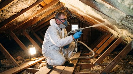 male using the blown-in technique to apply spray foam insulation