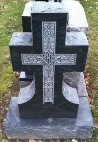 Gray stone memorial with an ornate engraved cross on the front