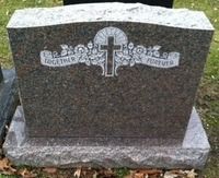 Gray granite gravestone with a cross and floral engraving in a cemetery