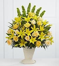 Yellow and white lily bouquet in a cream vase on a white table