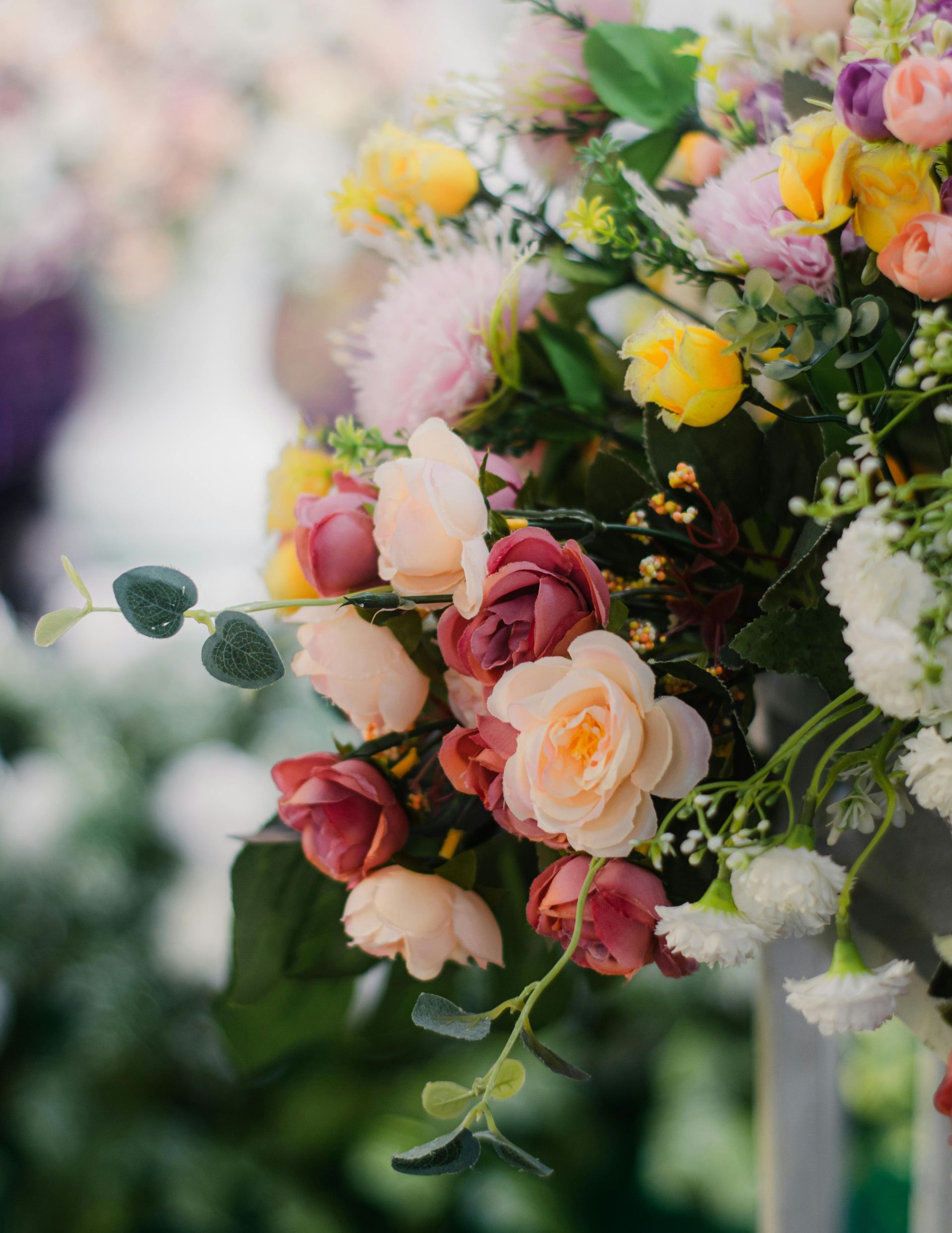 Pastel pink, yellow, and white flowers arranged in a lush bouquet outdoors