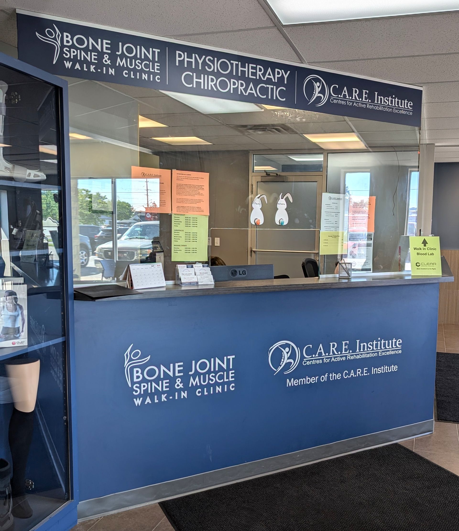 Bone Joint Spine & Muscle chiropractic reception desk with blue counter and waiting area signs.