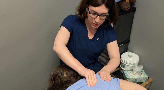 A nurse is stretching a patient 's leg with a purple rubber band.
