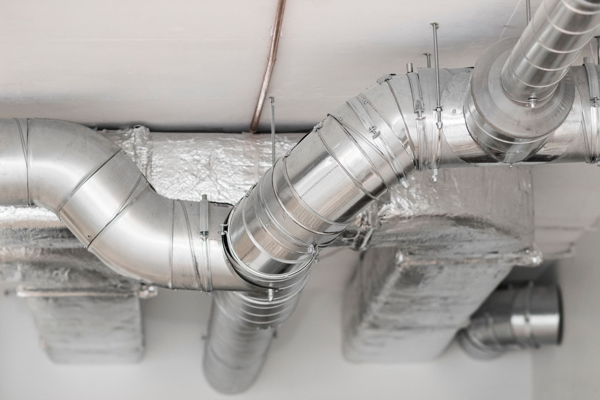 Conduits et bouches d'aération argentés du système CVC longeant un plafond dans un intérieur industriel