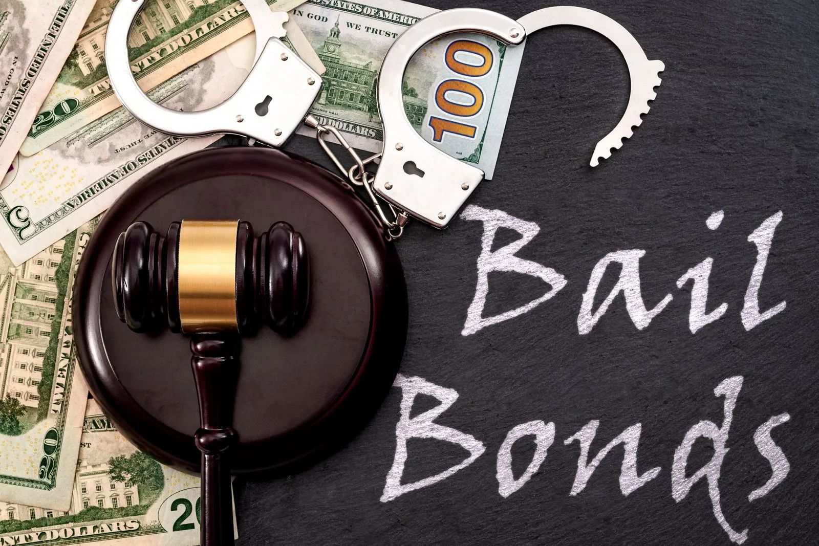 Gavel beside handcuffs, cash, and chalkboard reading “Bail Bonds”