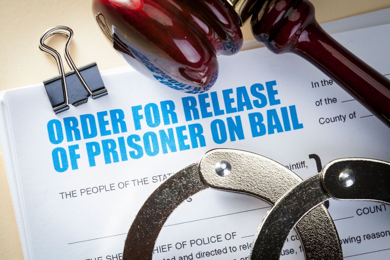 Judge’s gavel, handcuffs, and bail release order form on a desk
